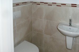 Gäste WC-Raum mit Botticino und rotem Glas